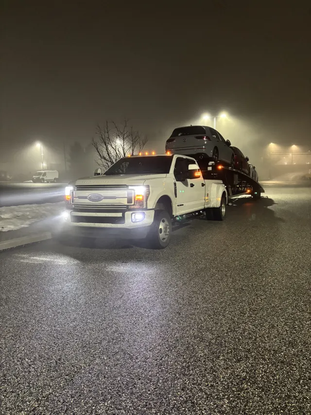 Loaded car hauler in fog at night, headlights on