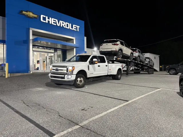Loaded car hauler at a dealership lot at night