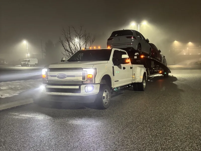 Nardical car hauler loaded with vehicles, headlights on in fog at night